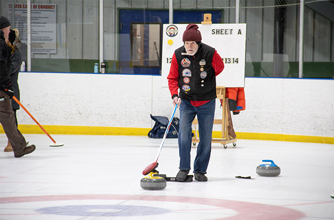 Gray bearded man on the ice curling